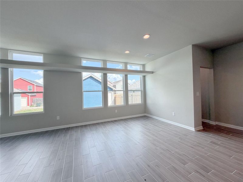 Spacious interior room featuring tile flooring, neutral wall tones, recessed lighting, and multiple windows