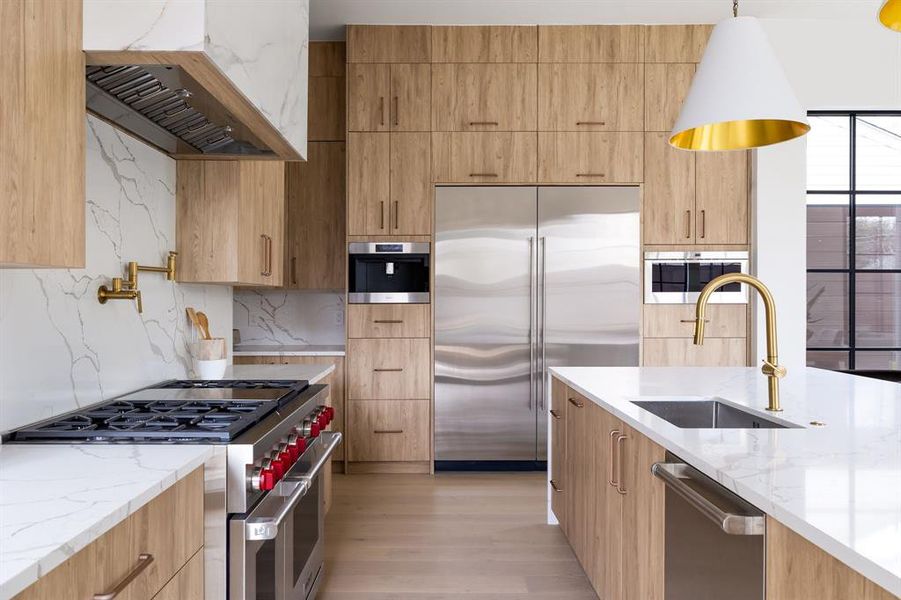 Kitchen with premium appliances, modern cabinets, a sink, and pendant lighting