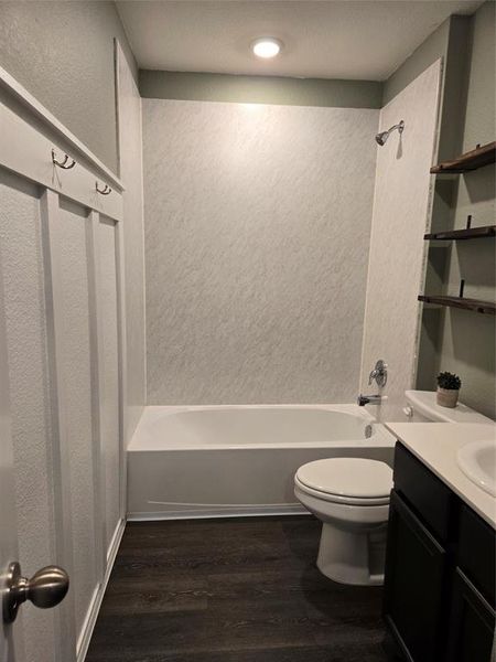 Full bathroom with shower / bathtub combination, vanity, hardwood / wood-style floors, and toilet