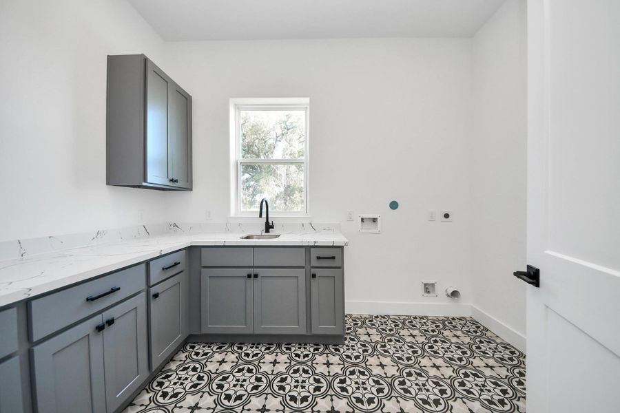Luxury laundry room with custom cabinetry, counter and sink.