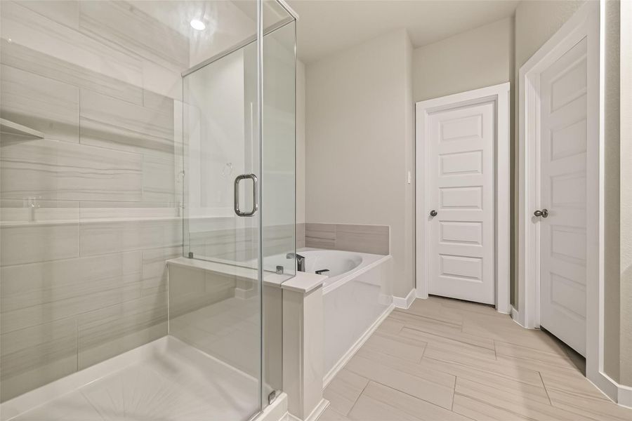 A closer view of the glass-enclosed shower shows its modern design, with a jetted tub located right beside it.