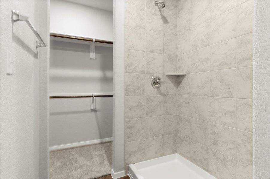 Full bathroom featuring tiled shower and a spacious closet