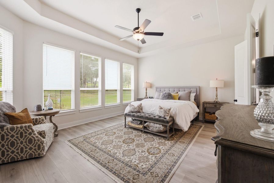 The primary suite serves as a private, sun-drenched wing of the home, featuring a wall of windows that lets you wake up to peaceful views of nature