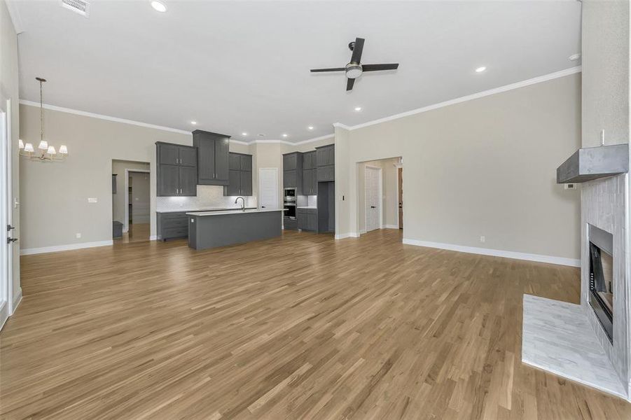 Unfurnished living room featuring sink, ornamental molding, a fireplace, and light hardwood / wood-style flooring