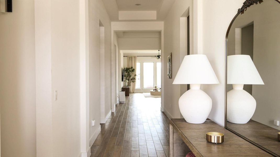 A graceful hallway extends towards a sun-drenched living area, offering a seamless flow within the residence. A graceful hallway extends towards a sun-drenched living area, offering a seamless flow within the residence.