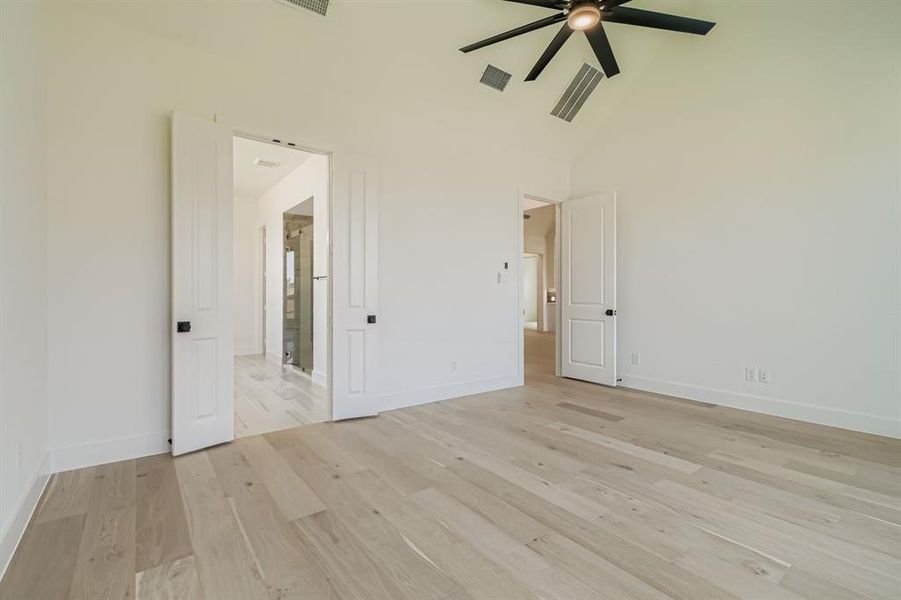Spare room featuring high vaulted ceiling, light wood-type flooring, and ceiling fan Spare room featuring high vaulted ceiling, light wood-type flooring, and ceiling fan