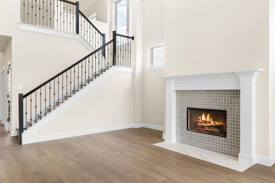 Stairs with a fireplace, hardwood / wood-style flooring, and a towering ceiling