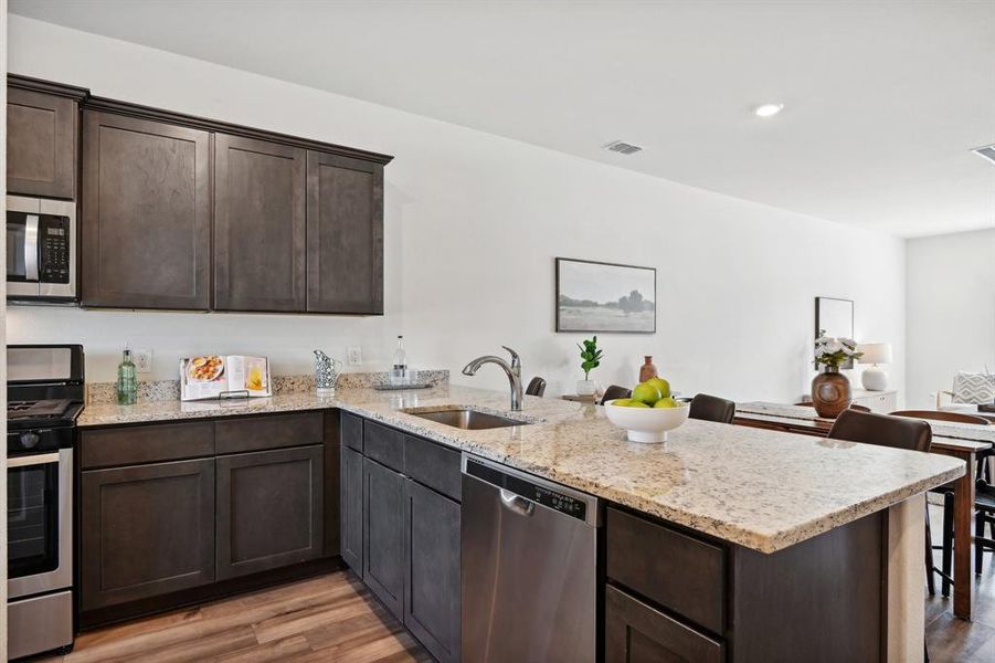 Kitchen featuring sink, kitchen peninsula, light hardwood / wood-style flooring, stainless steel appliances, and dark brown cabinetry