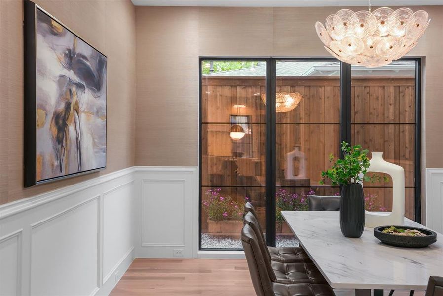 The property features elegant wainscoting and hardwood floors, complemented by a contemporary chandelier