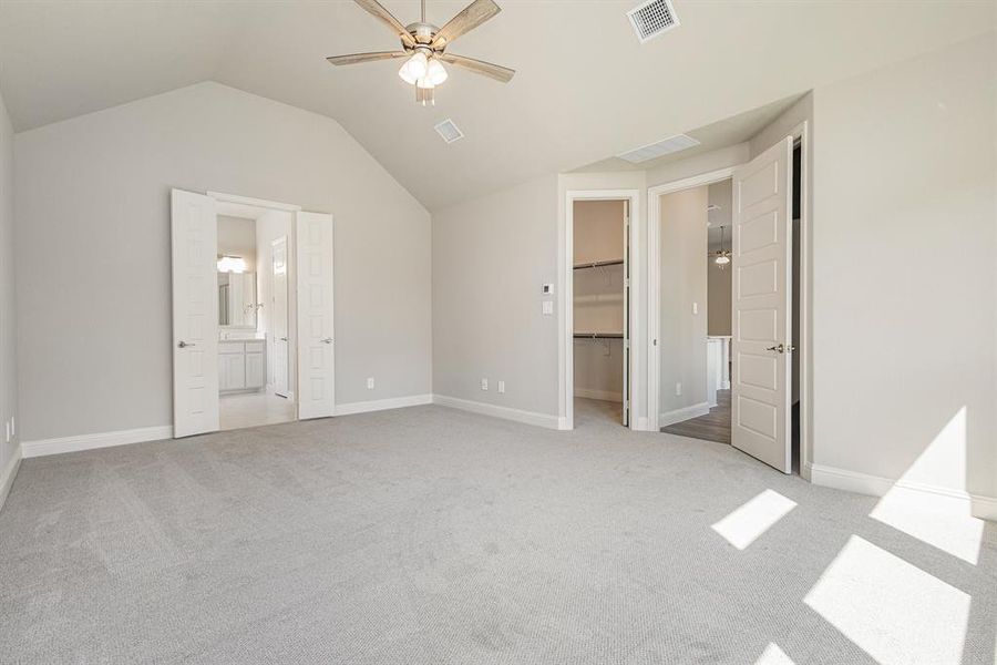 Unfurnished bedroom featuring a walk in closet, light colored carpet, ensuite bath, lofted ceiling, and ceiling fan Unfurnished bedroom featuring a walk in closet, light colored carpet, ensuite bath, lofted ceiling, and ceiling fan