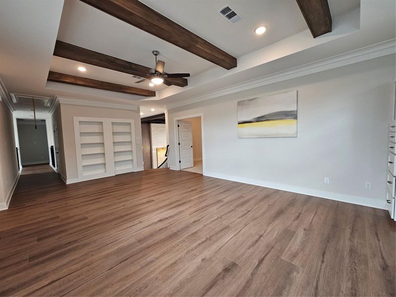 This spacious living area features elegant hardwood floors, exposed wooden ceiling beams, and built-in shelving. The neutral color palette and recessed lighting create a bright, inviting atmosphere. This spacious living area features elegant hardwood floors, exposed wooden ceiling beams, and built-in shelving. The neutral color palette and recessed lighting create a bright, inviting atmosphere.