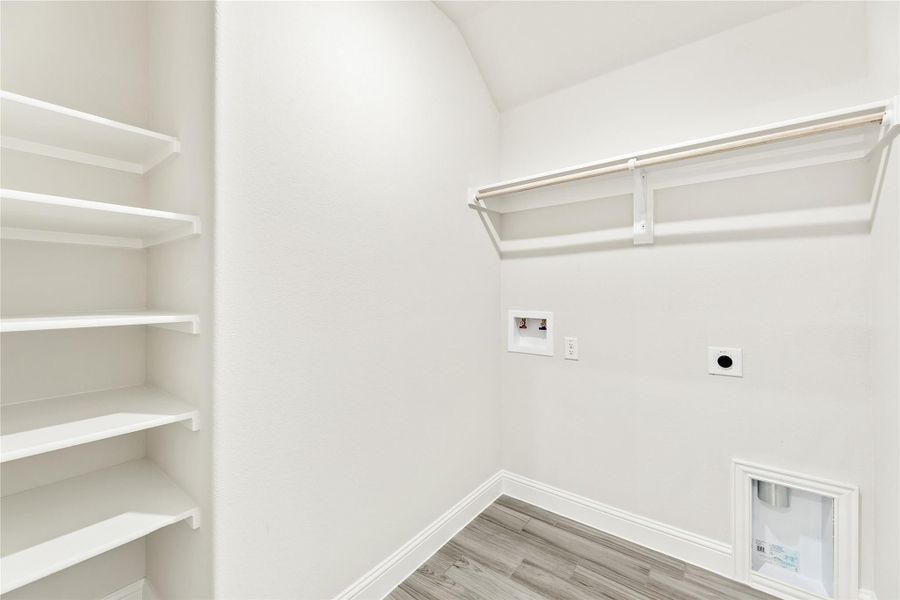 Laundry room with built-in shelves, hanging rod, washer and dryer hookups, and wood-look floors