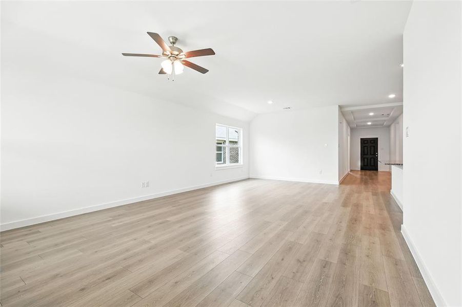 Unfurnished living room with light wood-type flooring, lofted ceiling, recessed lighting, and a ceiling fan Unfurnished living room with light wood-type flooring, lofted ceiling, recessed lighting, and a ceiling fan