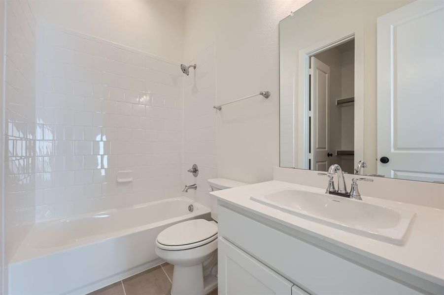 Full bathroom featuring vanity, toilet, tile patterned flooring, and tiled shower / bath