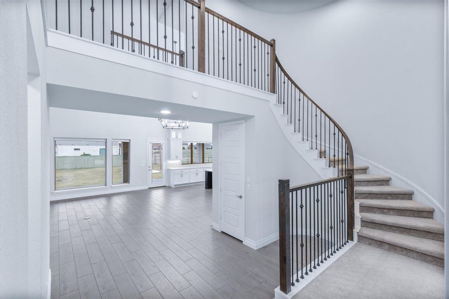 Stairs with wood finish floors, a chandelier, and a towering ceiling