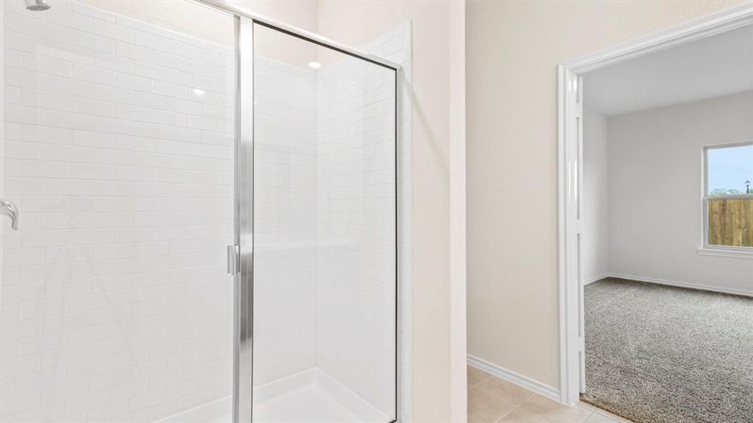 Walk-in shower with clear glass enclosure and white subway tile surround