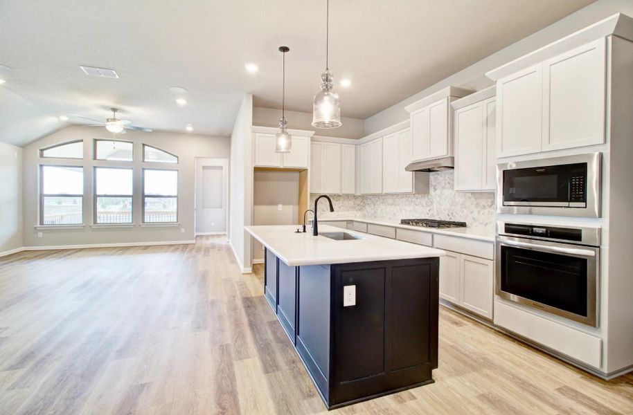 Kitchen with white cabinetry, stainless steel appliances, decorative backsplash, decorative light fixtures, and light wood-style floors Kitchen with white cabinetry, stainless steel appliances, decorative backsplash, decorative light fixtures, and light wood-style floors
