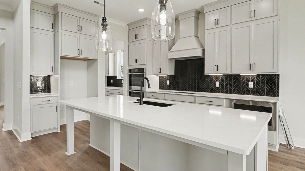 Kitchen with quartz countertops, pendant lighting, and tile backsplash Kitchen with quartz countertops, pendant lighting, and tile backsplash