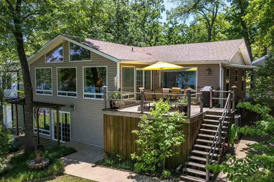 Multi-level exterior featuring a large elevated wood deck with perimeter railing and stairs