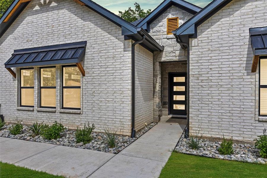 Entrance to property featuring stone siding and brick siding