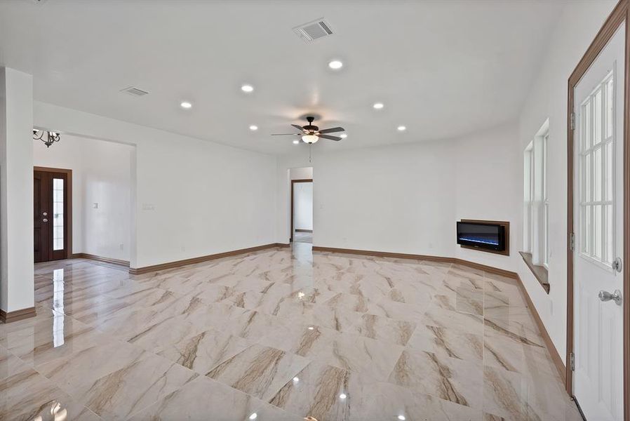 Unfurnished living room featuring a glass covered fireplace, recessed lighting, ceiling fan, and light marble finish floors
