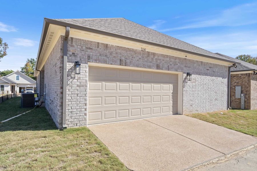 Brick exterior featuring a multi-car garage, concrete driveway, and wall-mounted outdoor lighting fixtures Brick exterior featuring a multi-car garage, concrete driveway, and wall-mounted outdoor lighting fixtures