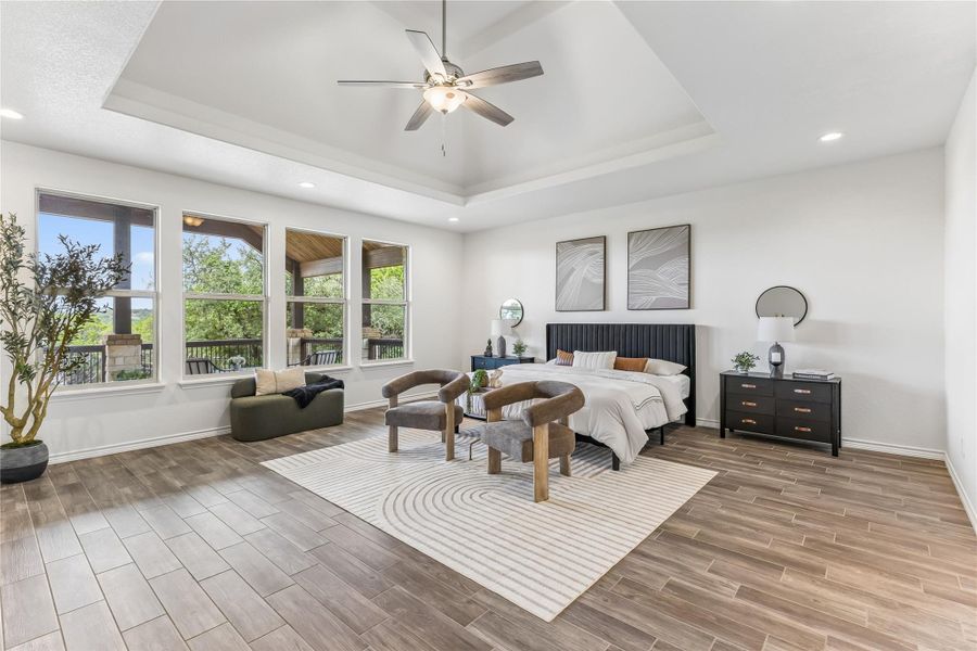 A spacious primary bedroom features tray ceilings, recessed lighting, and expansive windows offering verdant views.