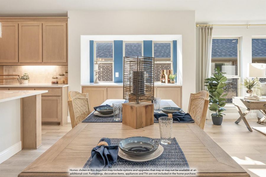 Dining area with wood table and woven chairs open to kitchen with light wood cabinets and large windows Dining area with wood table and woven chairs open to kitchen with light wood cabinets and large windows
