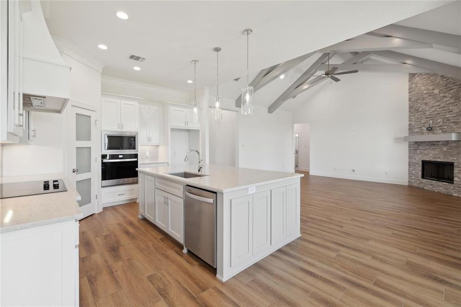 Kitchen featuring white cabinetry, sink, a center island with sink, appliances with stainless steel finishes, and vaulted ceiling with beams