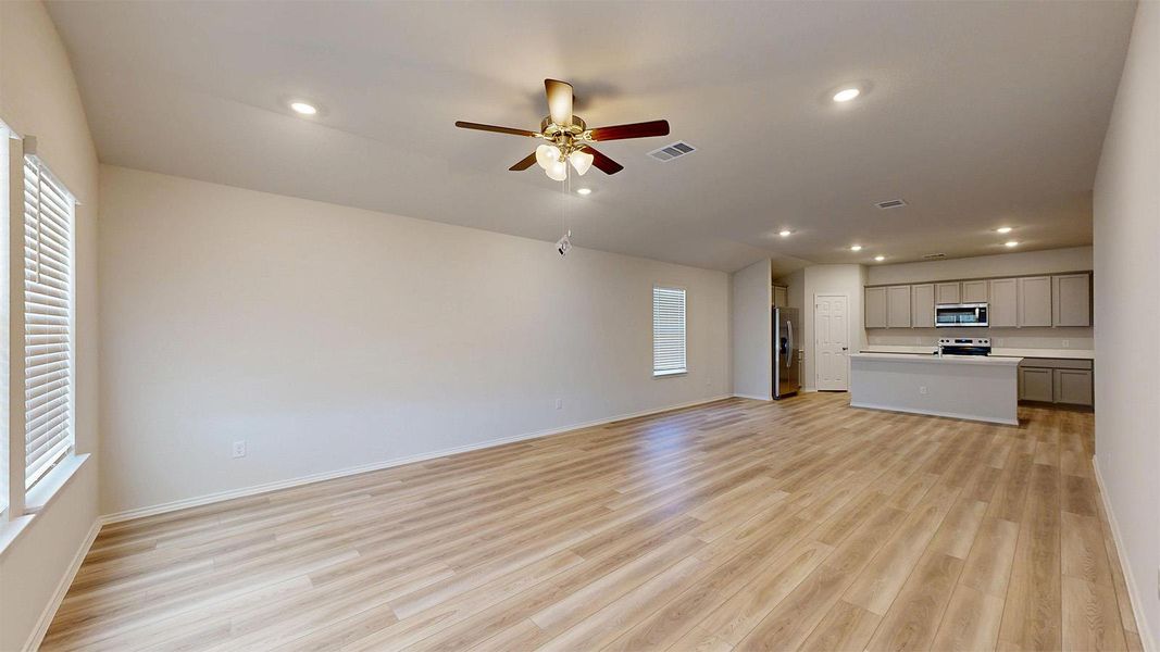 An open-concept layout unites the living area and a streamlined kitchen, featuring recessed lighting and durable laminate flooring.