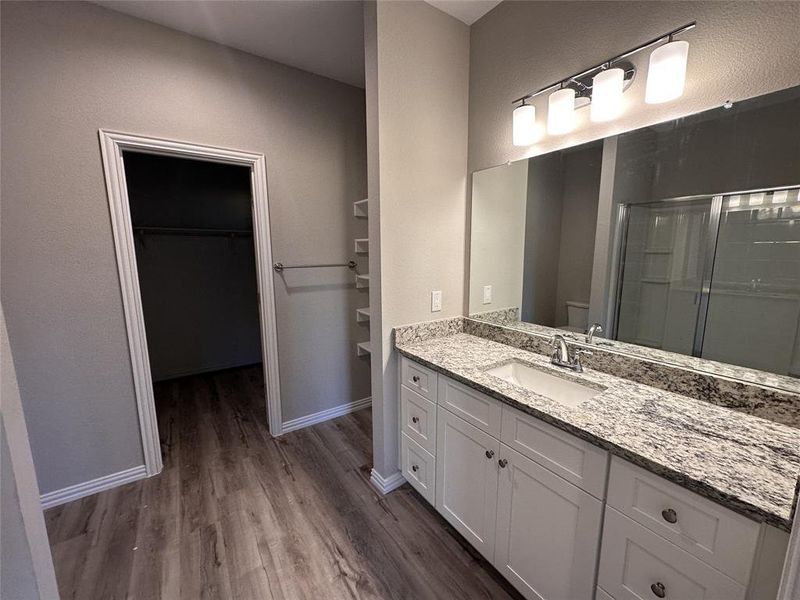 Bathroom featuring hardwood / wood-style flooring, vanity, toilet, and a shower with shower door