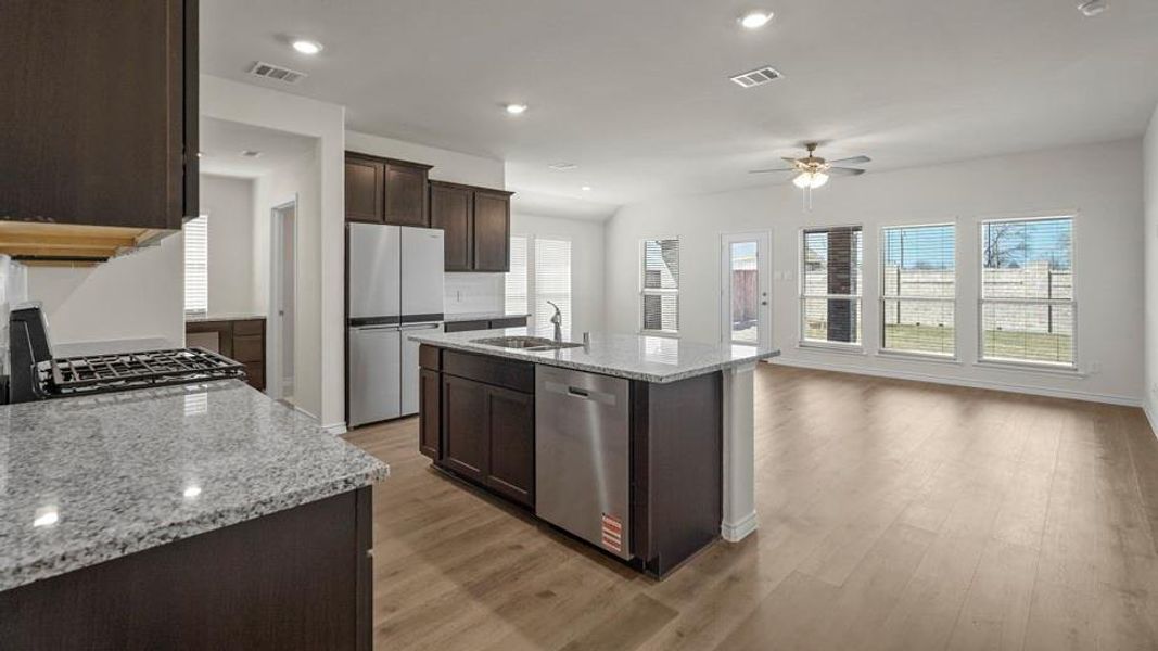 The kitchen features dark wood cabinetry, light granite countertops, and stainless steel appliances