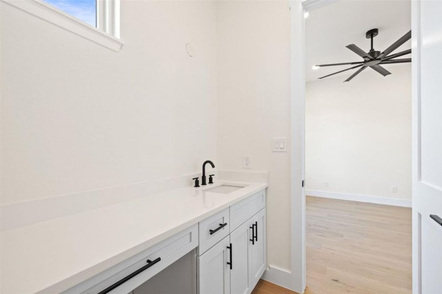 A well-appointed wet bar area, featuring bright countertops and sleek cabinetry, offers convenient entertaining. A well-appointed wet bar area, featuring bright countertops and sleek cabinetry, offers convenient entertaining.