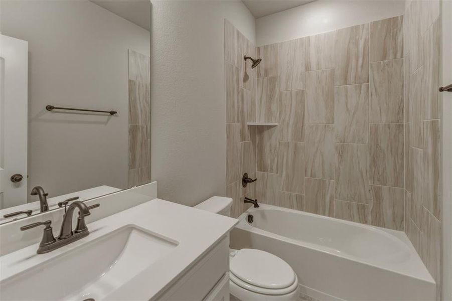 Bathroom featuring a white vanity with a rectangular sink and solid surface countertop, bronze finish plumbing fixtures, a full-width mirror, and a shower-over-tub with tiled surround Bathroom featuring a white vanity with a rectangular sink and solid surface countertop, bronze finish plumbing fixtures, a full-width mirror, and a shower-over-tub with tiled surround