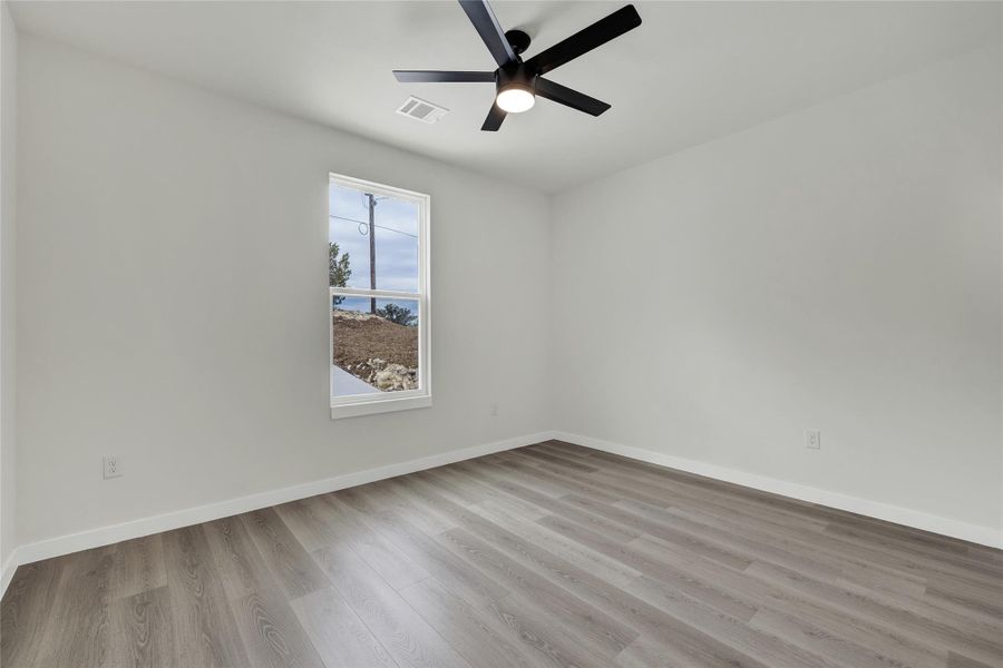 Empty room featuring light wood-style flooring and a ceiling fan