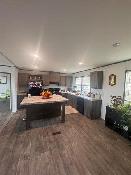 Kitchen with dark wood finish cabinetry, dark wood-style flooring, a kitchen bar, stove, and a kitchen island Kitchen with dark wood finish cabinetry, dark wood-style flooring, a kitchen bar, stove, and a kitchen island