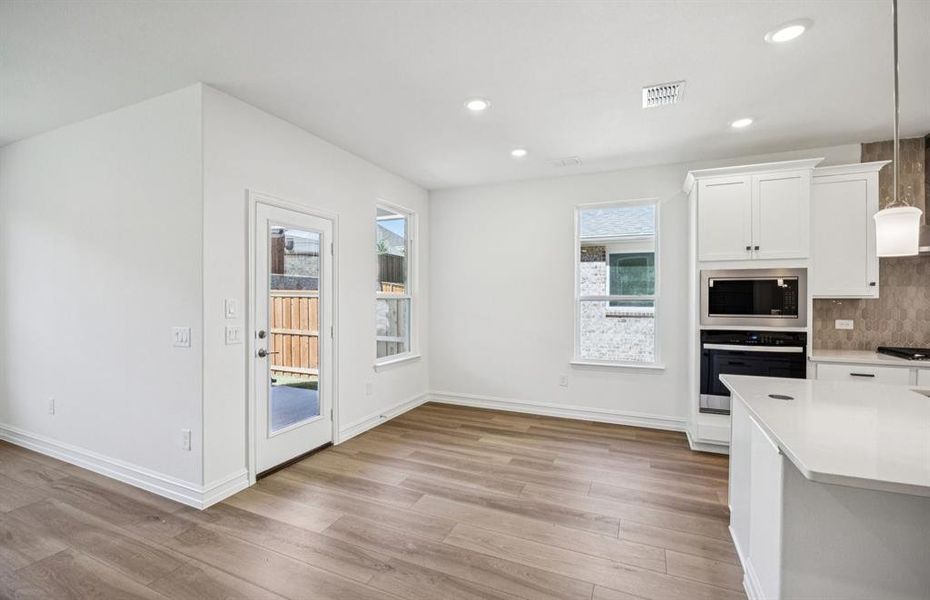 Open kitchen with adjoining nook featuring large windows and direct access to the backyard Open kitchen with adjoining nook featuring large windows and direct access to the backyard