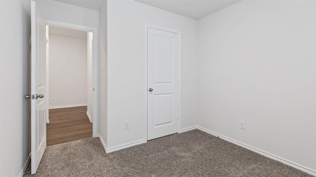 Unfurnished bedroom featuring baseboards and dark colored carpet