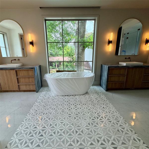 Two vanities, one tub set dead-center at the window, this primary bathroom is designed around the view as much as the fixtures. A patterned tile runway carries you straight to it. Two vanities, one tub set dead-center at the window, this primary bathroom is designed around the view as much as the fixtures. A patterned tile runway carries you straight to it.