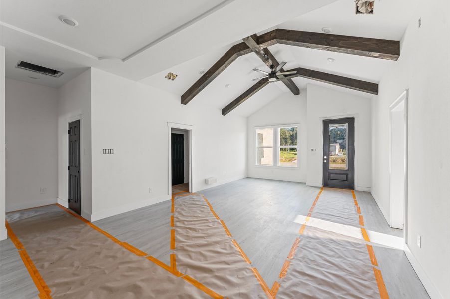 Bright and open living area with soaring cathedral ceilings and warm wood accents. High cathedral ceilings in living room. Photos are representative of the same floor plan built by this builder. Finishes will be the same or similar.