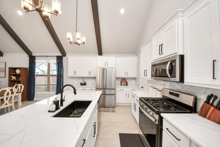 Elegant kitchen with white shaker cabinets, black hardware, matte-black faucet and sink, with quartz countertops