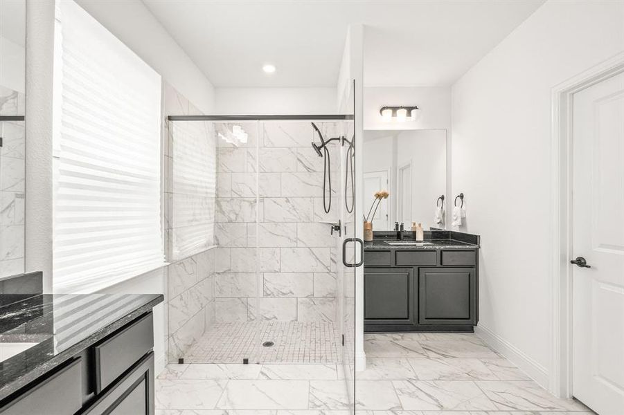 Bathroom with two vanities, a stall shower, and light marble finish floors