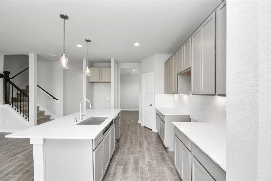 Culinary haven, featuring granite countertops, a tile backsplash, stainless steel appliances (to be installed), and 42” upper cabinets. Sample photo of completed home with similar floor plan. Actual colors and selections may vary.