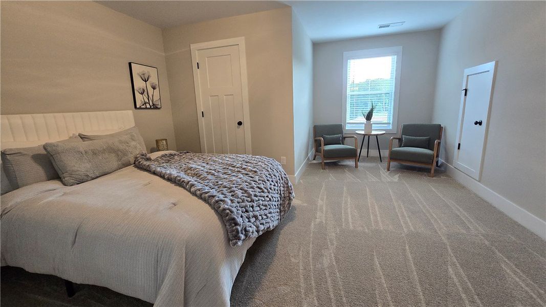 A well-lit bedroom features plush carpeting, a com A well-lit bedroom features plush carpeting, a com