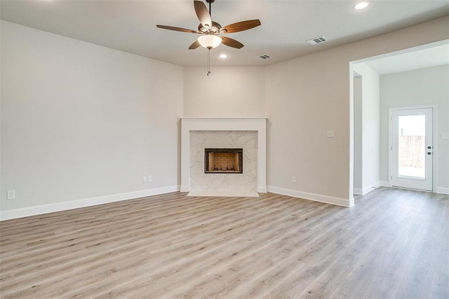 Unfurnished living room featuring a premium fireplace, light hardwood / wood-style flooring, and ceiling fan