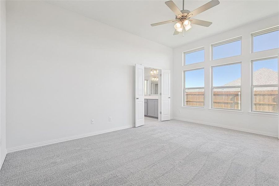 Carpeted spare room with plenty of natural light and ceiling fan