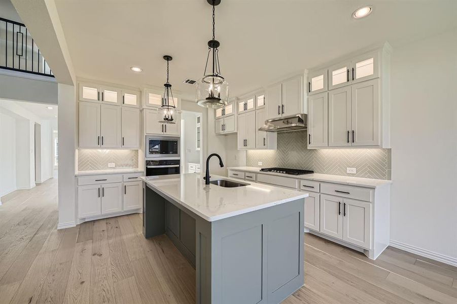 Kitchen featuring white cabinets, sink, a center island with sink, and stainless steel appliances