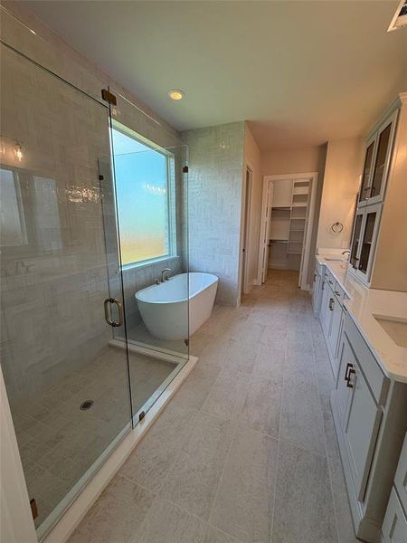 Full bath with a shower stall, a spacious closet, a freestanding tub, double vanity, and recessed lighting Full bath with a shower stall, a spacious closet, a freestanding tub, double vanity, and recessed lighting
