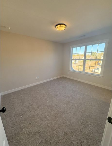 Carpeted spare room featuring baseboards