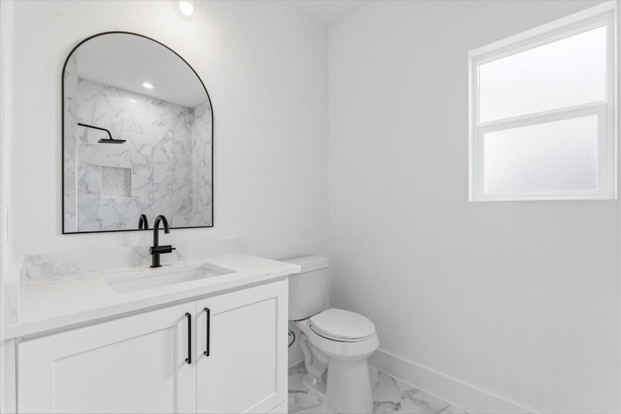 Upstairs bathroom featuring a charming shower/tub combo, a spacious vanity, and a sleek modern mirror. Frosted glass window adds privacy while still allowing plenty of natural light to fill the space.